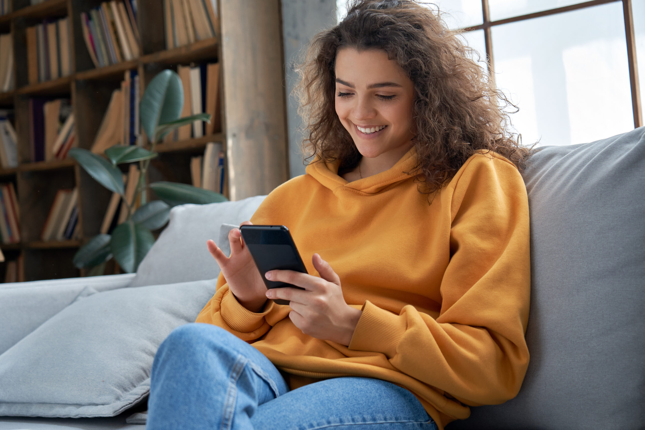 Young woman checking her phone on the couch